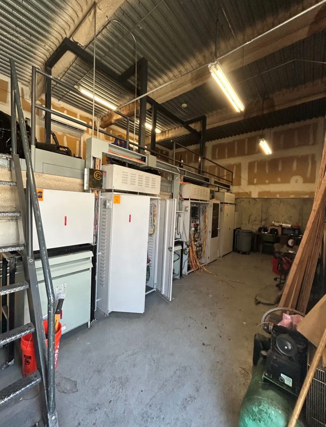 Elevator control cabinets with exposed conduit and machine-room equipment.